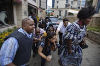 Civilians helped by plain-clothes security forces flee the scene at a hotel complex in Nairobi, Kenya Tuesday, Jan. 15, 2019. Terrorists attacked an upscale hotel complex in Kenya's capital Tuesday, sending people fleeing in panic as explosions and heavy gunfire reverberated through the neighborhood. (AP Photo/Ben Curtis)