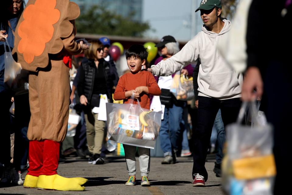 A child carrying a big bag walks among a lot of people outdoors.