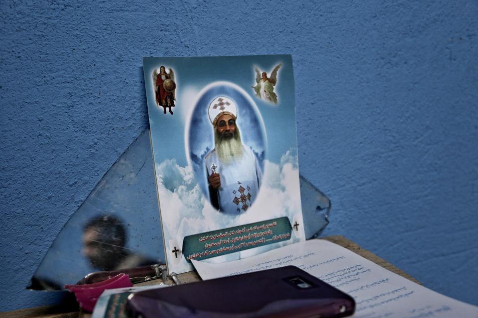 A Christian man, reflected in a mirror, who fled el-Arish due to fighting sits near a photo of priest who was killed by militants, in his newly rented apartment in Ismailia, 120 kilometers (75 miles) east of Cairo, Egypt, Sunday, Feb. 26, 2017. Egyptian Christians fearing attacks by Islamic State militants are fleeing the volatile northern part of the Sinai Peninsula for a fourth day, after a string of sectarian killings there sent hundreds fleeing and raised accusations the government is failing to protect the minority. (AP Photo/Nariman El-Mofty)