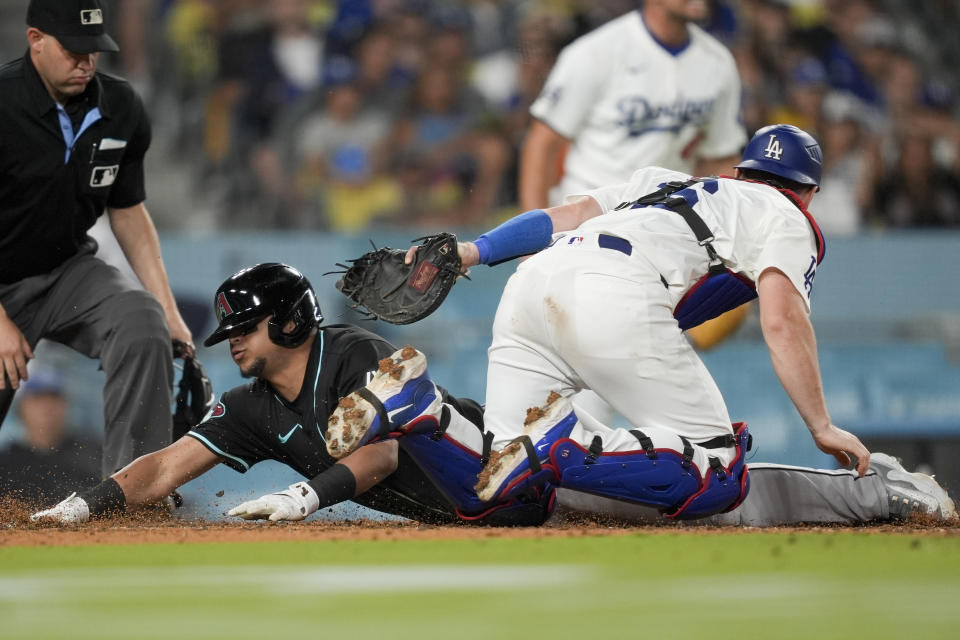 Arizona Diamondbacks' Gabriel Moreno, left, slides home past Los Angeles Dodgers catcher Will Smith to score off a bunt single by Jake McCarthy during the eighth inning of a baseball game against the Los Angeles Dodgers, Tuesday, July 2, 2024, in Los Angeles. (AP Photo/Ryan Sun)