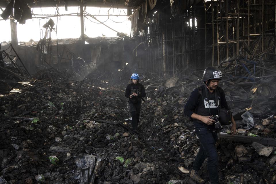 Journalists walk inside a destroyed warehouse for storing food, after an attack from Russia twelve days ago in Brovary, on the outskirts of Kyiv, Ukraine, Tuesday, March 29, 2022. (AP Photo/Rodrigo Abd)