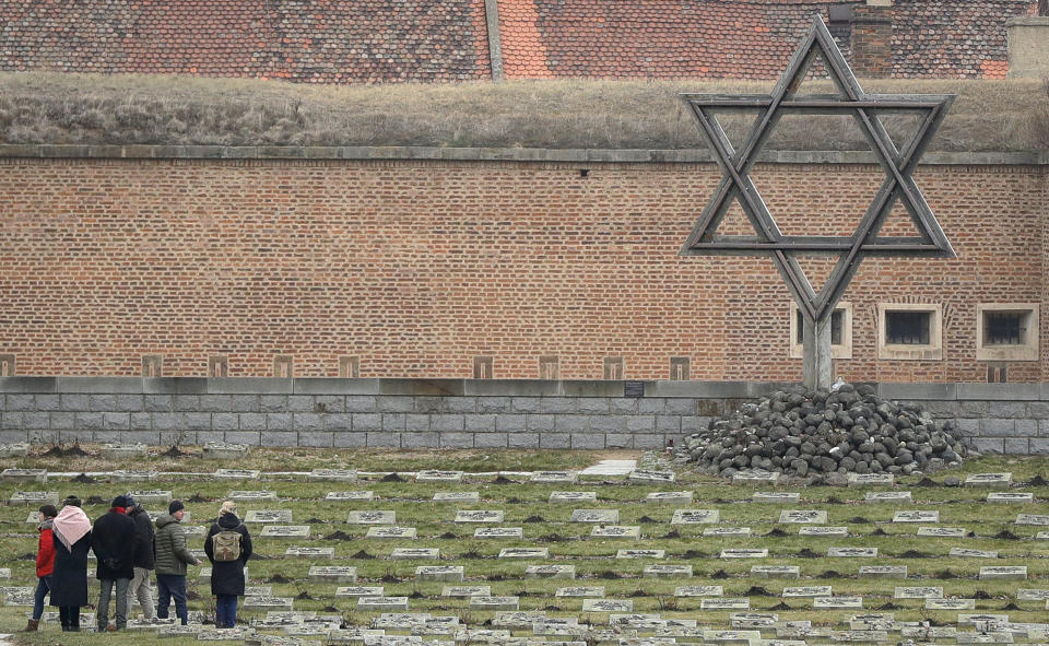 Visitors walk through the cemetery of the former Nazi concentration camp in Terezin, Czech Republic, Thursday, Jan. 24, 2019. A unique collection of some 4,500 drawings by children who were interned at the Theresienstadt concentration camp during the Holocaust now displayed in the Pinkas Synagogue, still attracts attention even after 75 years since their creation. The drawings depict the everyday life as well hopes and dreams of returning home. (AP Photo/Petr David Josek)