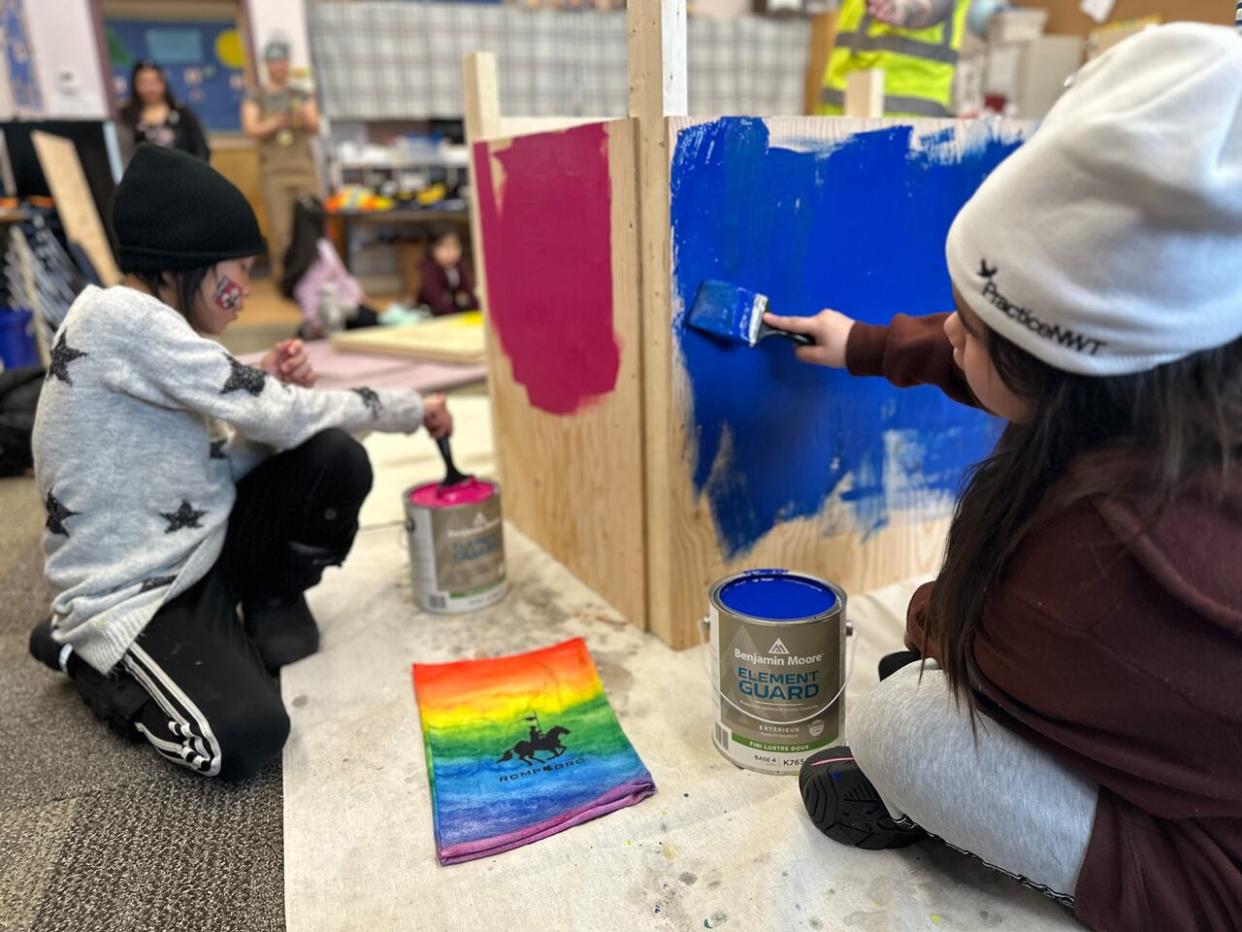 Maggie Drybones, right, and another young child, left, helped paint a dog house for Maggie's dog, Bear, in bright colours. (Liny Lamberink/CBC - image credit)