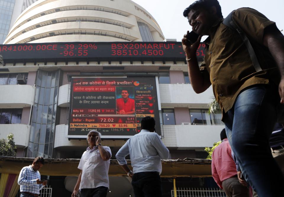 People walk in front of the Bombay Stock Exchange (BSE) in Mumbai, India, Friday, Feb. 28, 2020. Asian stock markets fell further Friday on spreading virus fears, deepening an global rout after Wall Street endured its biggest one-day drop in nine years. (AP Photo/Rajanish Kakade)