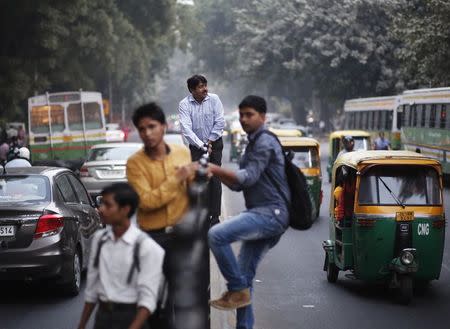 Pedestrians climb a fence on a road divider to cross a busy road in New Delhi October 28, 2014. REUTERS/Anindito Mukherjee