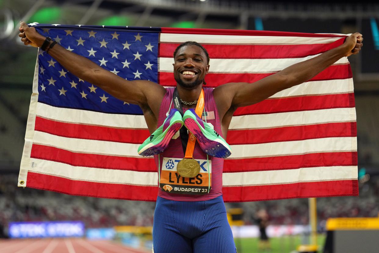 Noah Lyles poses with the United States flag after winning the men's 200-meter race at the 2023 World Athletics Championships at National Athletics Centre in Budapest, Hungary on Aug. 25, 2023.