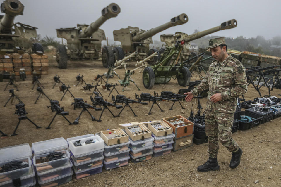 An Azerbaijani Army officer shows weapons and equipment surrendered by Armenian forces in Nagorno-Karabakh displayed in Signag village, Azerbaijan, Sunday, Oct. 1, 2023. Armenian forces in Nagorno-Karabakh laid down their weapons after a lightning military operation in which Azerbaijan reclaimed control of the breakaway region after three decades of separatist rule. (AP Photo/Aziz Karimov)