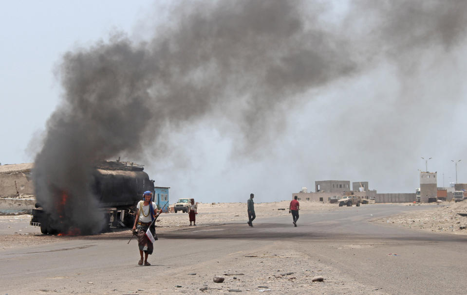 FILE - In this Aug. 30, 2019 file photo, people inspect an oil tanker truck set ablaze during recent clashes between Yemeni southern separatists and government forces in near Aden, Yemen. Fighting between their allies in southern Yemen has opened a gaping wound in the Saudi Arabia and the United Arab Emirates’ coalition fighting the country’s rebels. If they can’t fix it, it threatens to further fragment the country into smaller warring pieces. (AP Photo/Wail al-Qubaty, File)