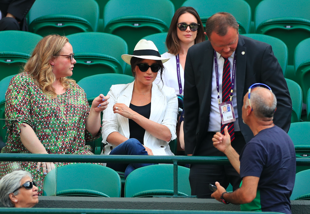 A bodyguard tells a tennis fan not to take pictures of Meghan Markle (PA)