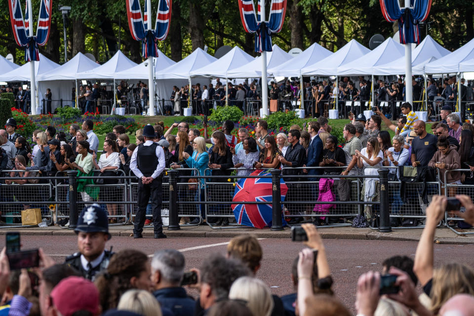 LONDON, ENGLAND - SEPTEMBER 14: Members of the media and the public wait to watch the ceremonial procession carrying the coffin of Queen Elizabeth II from Buckingham Palace to the Palace of Westminster on September 14, 2022 in London, United Kingdom. Queen Elizabeth II's coffin is taken in procession on a Gun Carriage of The King's Troop Royal Horse Artillery from Buckingham Palace to Westminster Hall where she will lay in state until the early morning of her funeral. Queen Elizabeth II died at Balmoral Castle in Scotland on September 8, 2022, and is succeeded by her eldest son, King Charles III.  (Photo by Carl Court/Getty Images)