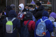 A man holds the Olympic mascot Bing Dwen Dwen doll walks by hundreds of residents line up to visit a store selling 2022 Winter Olympics memorabilia in Beijing, Monday, Feb. 7, 2022. The race is on to snap up scarce 2022 Winter Olympics souvenirs. Dolls of mascot Bing Dwen Dwen, a panda in a winter coat, sold out after buyers waited in line overnight in freezing weather. (AP Photo/Andy Wong)