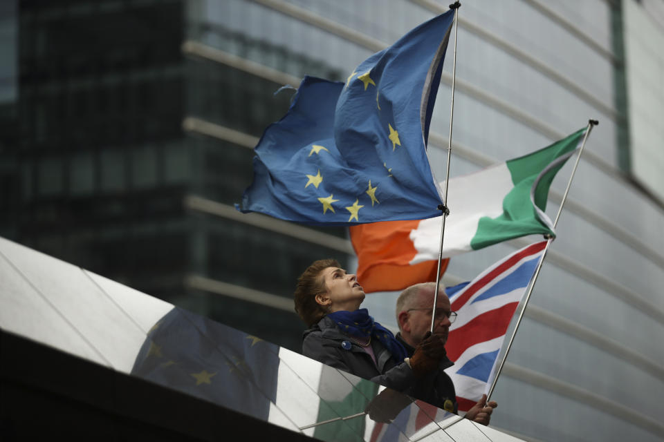 Two anti-Brexit people hold EU, Ireland and Union Flags stand outside the European Commission in Brussels, Friday, Oct. 11, 2019. EU negotiator Michel Barnier says that he had a "constructive meeting" with British Brexit envoy Stephen Barclay and underscored the cautious optimism since Thursday's meeting between British Prime Minister Boris Johnson and his Irish counterpart Leo Varadkar. (AP Photo/Francisco Seco)