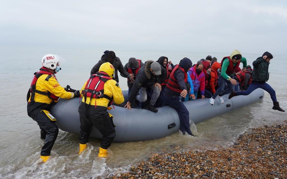 People thought to be migrants are helped ashore by lifeboat crew members, after arriving on a dinghy at a beach in Dungeness on Saturday November 20, 2021 - Gareth Fuller 