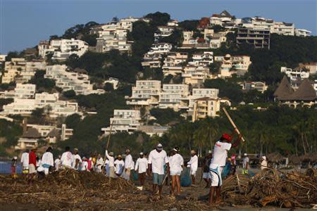 A group of disaster victims, who are hired by the municipality, remove debris from the beach at Diamante Zone in Acapulco, October 2, 2013. REUTERS/Edgard Garrido