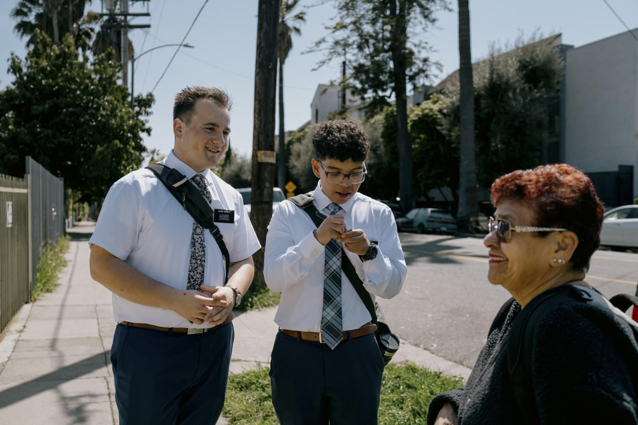 Alec Crawley, left, and Andres Gonzalez, missionaries for the Church of Jesus Christ of Latter-day Saints, give a woman a card with their phone number, at the edge of the Koreatown neighborhood in Los Angeles, March 26, 2024. (Isadora Kosofsky/The New York Times)