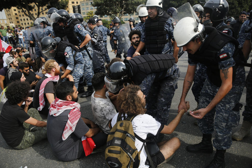 Police negotiate with anti-government protesters to unblock a main highway in Beirut, Lebanon, Saturday, Oct. 26, 2019. The removal of the roadblocks on Saturday comes on the tenth day of protests in which protesters have called for civil disobedience until the government steps down. (AP Photo/Hussein Malla)