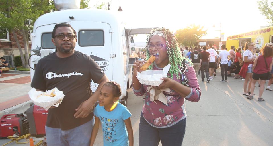 Torrey Hodges, Nicolette Hodges, 7, and Dee Sims enjoy food during the opening day of the Ames Main Street Farmers' Market on May 17.