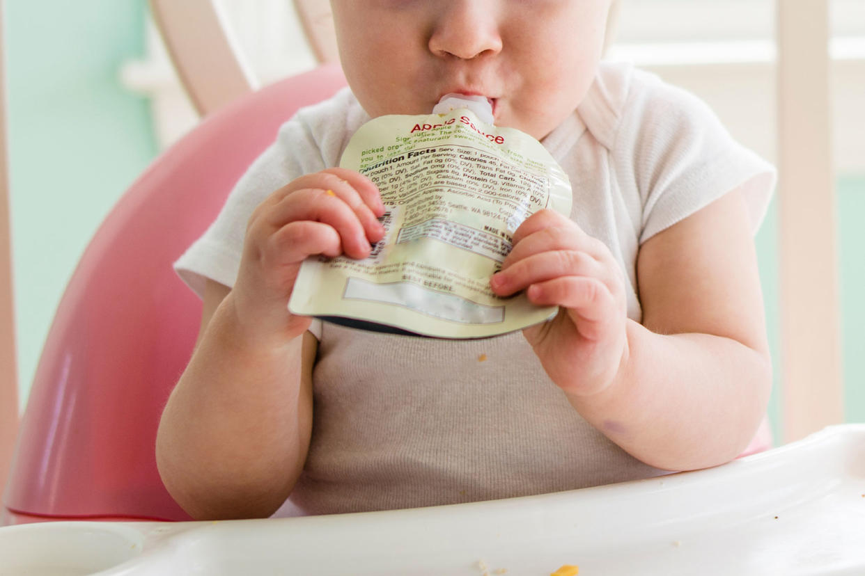 Baby girl eating apple sauce from pouch Getty Images/Cavan Images