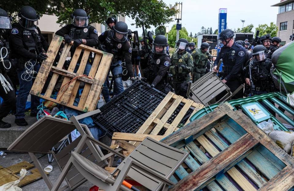 Police remove pallets as they continue to move out protesters from the plaza outside the UCI physical sciences building.