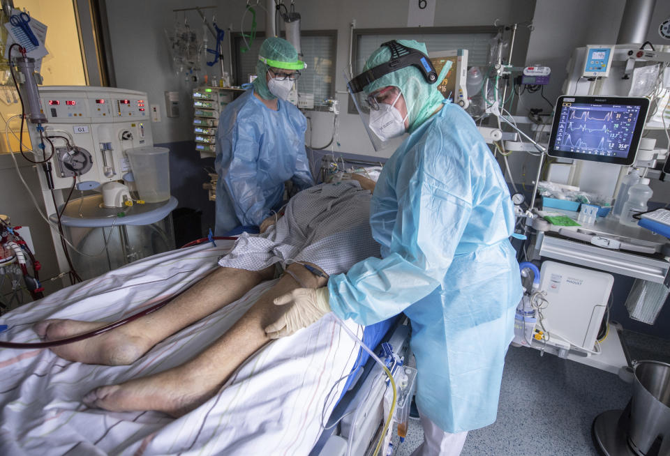 Nurses care for a patient with severe COVID-19 disease in the coronavirus intensive care unit at the hospital in Fulda, Germany, Wednesday, Feb. 16, 2022. (Boris Roessler/dpa via AP)