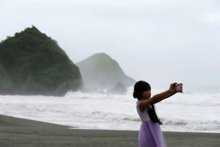 Waves are seen behind a girl as Typhoon Nepartak approaches, in Yilan, Taiwan July 7, 2016. REUTERS/Tyrone Siu