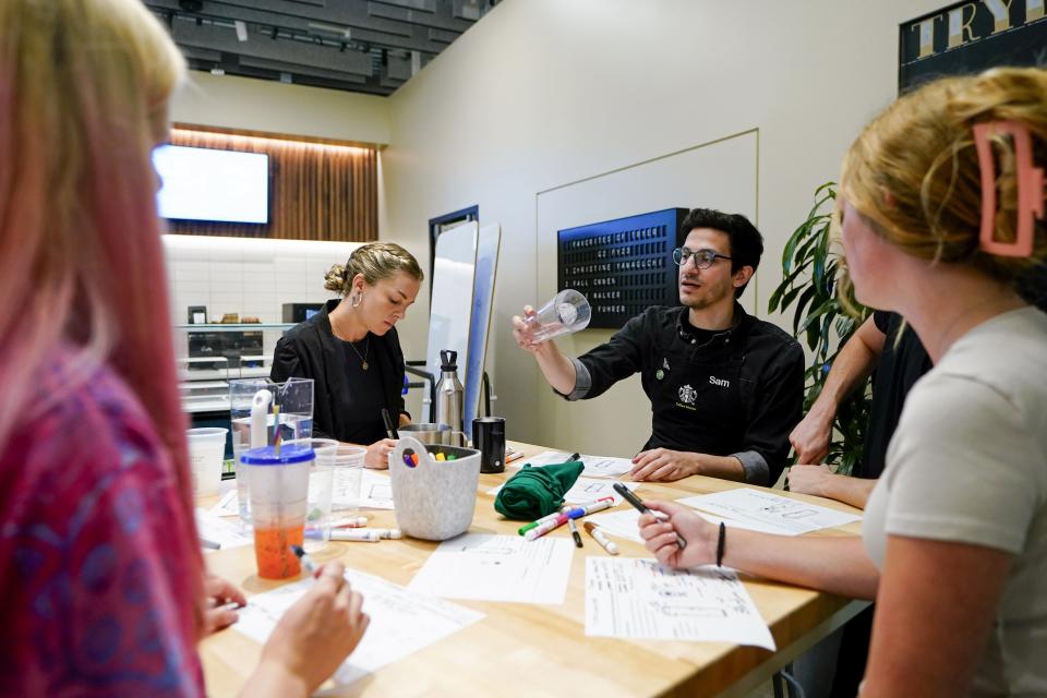 Starbucks reusables business strategy senior manager Mary-Catherine Burton, left, takes notes as Tryer Lab partner Sam Farahani discusses design during a personal cup focus group at the Tryer Center at Starbucks headquarters, Wednesday, June 28, 2023, in Seattle. The company's goals is to cut waste, water use and carbon emissions in half by 2030. (AP Photo/Lindsey Wasson)