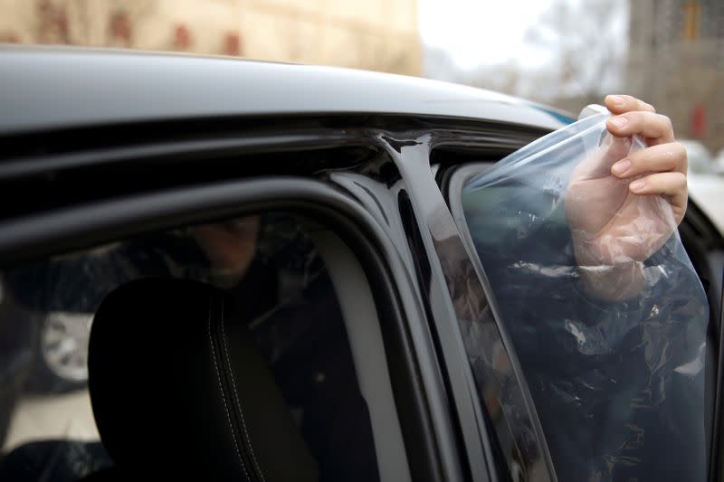 Staff member installs plastic shield inside a vehicle at a service centre of car-hailing service Didi Chuxing, as the country is hit by an outbreak of the new coronavirus, in Beijing