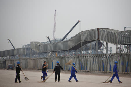 FILE PHOTO: Workers walk in front of the Hebei Zongheng Iron and Steel plant that is under construction at the Tangshan Fengnan Economic Development Zone, Hebei province, China, August 22, 2018. REUTERS/Thomas Peter/File Photo