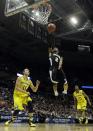 Wofford guard Karl Cochran (2) drives to the basket against Michigan guard Nik Stauskas (11) during the second half of a second round NCAA college basketball tournament game against the Michigan Thursday, March 20, 2014, in Milwaukee. At right is Michigan guard Derrick Walton Jr. (10). (AP Photo/Morry Gash)