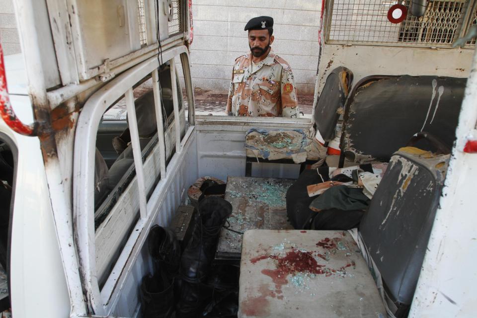 A Pakistani security officer looks at a vehicle targeted by militants in Karachi, Pakistan in Karachi, Pakistan. Police said several members of the country's security forces have been killed in separate attacks in the southern city of Karachi. (AP Photo/Fareed Khan)