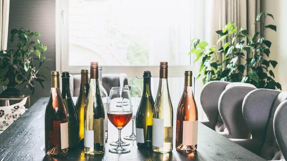 Variety of wine bottles and glasses on table in modern living room