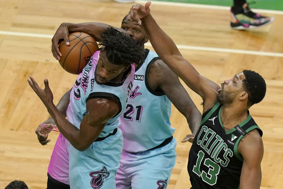 Miami Heat's Jimmy Butler, left, grabs a rebound as Boston Celtics' Tristan Thompson, right, vies for the ball while Heat's Dewayne Dedmon, behind, looks on in the first half of a basketball game, Sunday, May 9, 2021, in Boston. (AP Photo/Steven Senne)