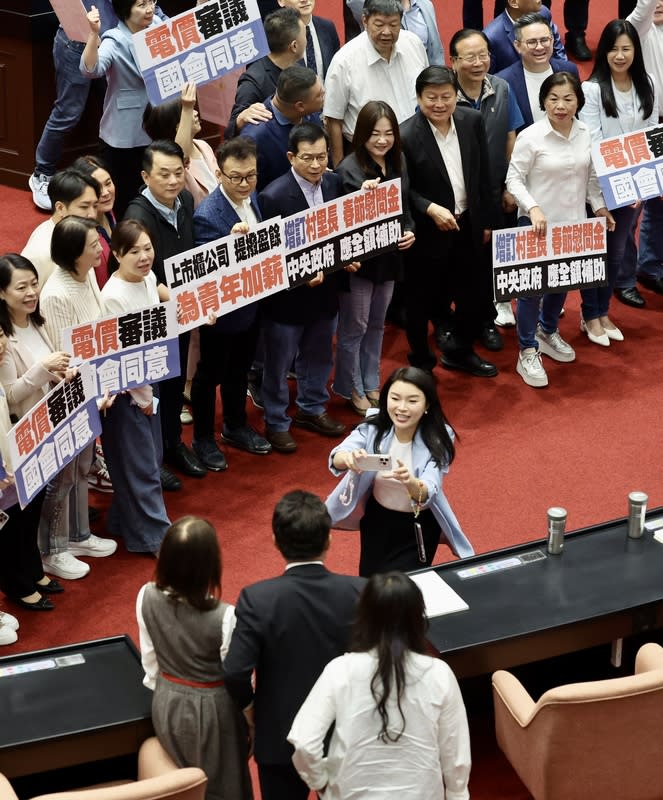 國民黨團提案電價漲跌須經立院同意（2） 立法院會3日上演表決大戰，國民黨團要求將攸關電 價調漲需送立院同意的電業法修正案抽出逕付二讀， 民眾黨團表態贊成。表決結果，藍白以人數優勢通 過，國民黨團的電業法修正草案逕付二讀。圖為表決 後國民黨立委張嘉郡（中）拿出手機請旁人幫忙拍 照。 中央社記者王飛華攝  113年5月3日 