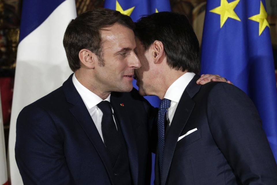 FILE - In this Thursday, Feb. 27, 2020 file photo, French President Emmanuel Macron, left, puts his arm around the shoulder of Italian Premier Giuseppe Conte and gives him a kiss on both cheeks during a joint press conference on the occasion of a French-Italian summit in Naples, southern Italy. French President Emmanuel Macron leaned in to give Premier Giuseppe Conte the Italian double-cheek kiss not just once, but at two separate moments during a Franco-Italian summit in Naples this week. It was much more than a greeting; it was a signal to citizens not to fear their neighbors as a new virus from China spreads, with Italy established as Europe’s hotspot. (AP Photo/Andrew Medichini, File)