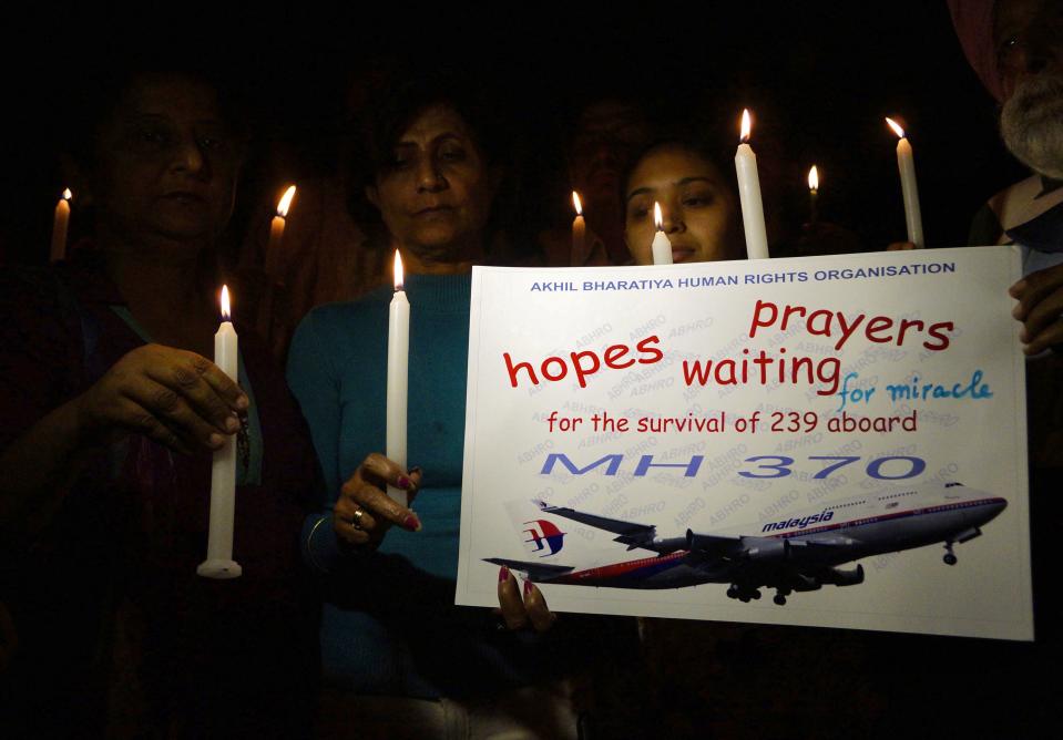 Members of Akhil Bharatiya Human Rights Organisation hold candles and placard as they take part in a candle light vigil for the well-being of passengers onboard missing Malaysia Airlines Flight MH370, in Amritsar