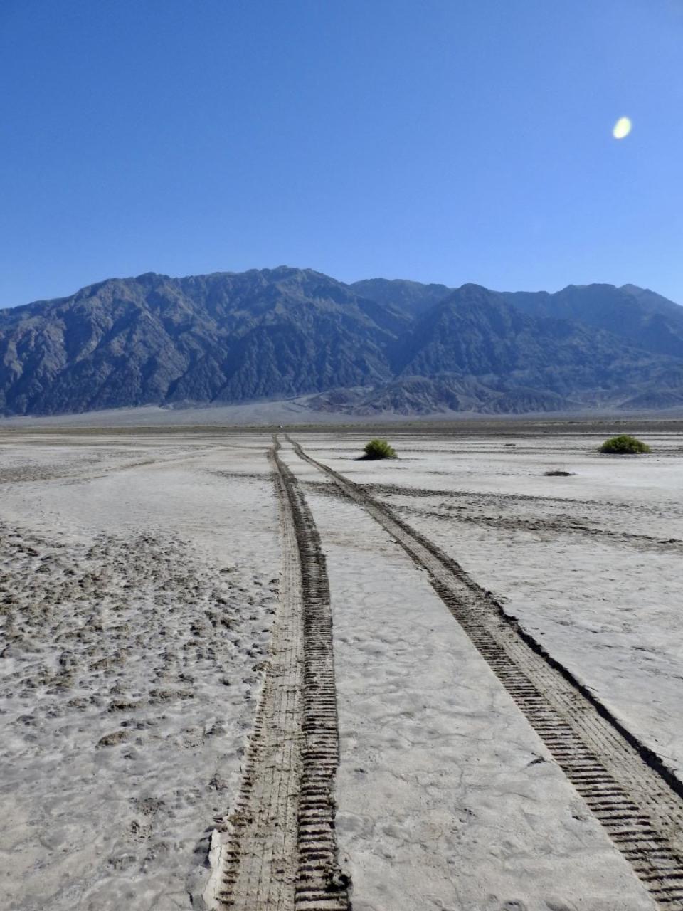 The dual tracks of the car that had gotten stuck and the skid steer used to remove it from a salt flat in Death Valley National Park. / Credit: National Park Service