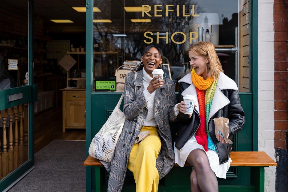 Two women laughing outside a store - Copyright: SolStock/GettyImages