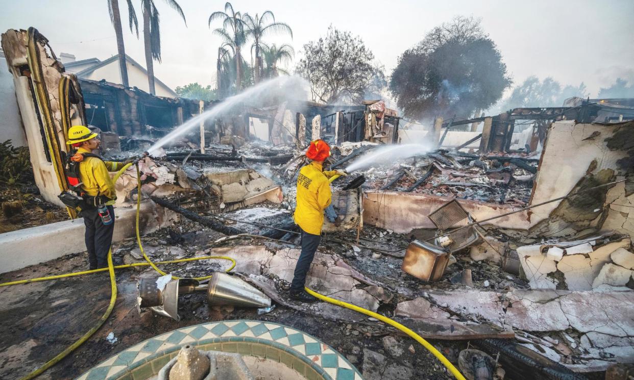 <span>Firefighters hose down hot spots at a house destroyed by the Hawarden fire in Riverside, California, on 21 July 2024.</span><span>Photograph: Terry Pierson/AP</span>