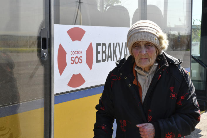 A woman waits to get on a bus during an evacuation of civilians on a road near Slovyansk, eastern Ukraine, Wednesday, May 4, 2022. (AP Photo/Andriy Andriyenko)