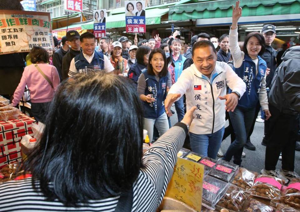 國民黨總統候選人侯友宜（右前）16日到台北市南京公寓市場掃街拜票，受到攤商熱烈歡迎。（趙雙傑攝）