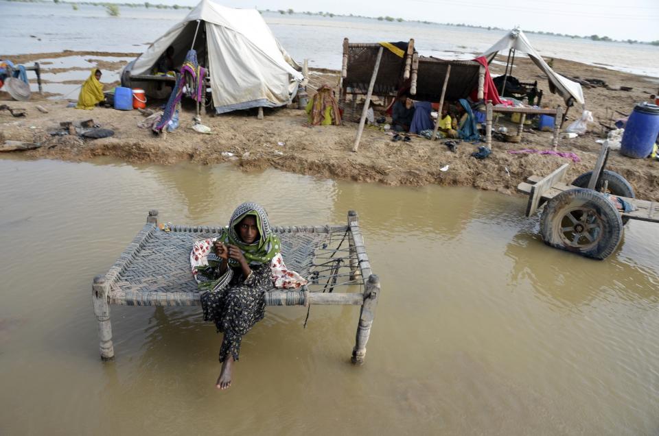FILE - A woman, surrounded by floodwaters, sits near her belongings, in Sohbat Pur city, a district of Pakistan's southwestern Baluchistan province, Sep. 3, 2022. The flooding in Pakistan killed at least 1,700 people, destroyed millions of homes, wiped out swathes of farmland, and caused billions of dollars in economic losses. (AP Photo/Zahid Hussain, File)