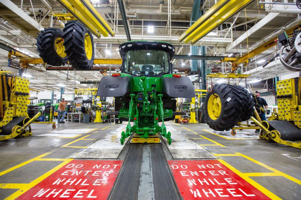 Wheels drop down from above as workers assemble a tractor at John Deere's Waterloo assembly plant.