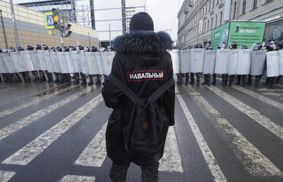 A man with a sign 'Navalny' on his back stands in front of riot policemen blocking the way to protester during a protest against the jailing of opposition leader Alexei Navalny in St. Petersburg, Russia, Sunday, Jan. 31, 2021. Thousands of people took to the streets Sunday across Russia to demand the release of jailed opposition leader Alexei Navalny, keeping up the wave of nationwide protests that have rattled the Kremlin. Hundreds were detained by police. (AP Photo/Dmitri Lovetsky)