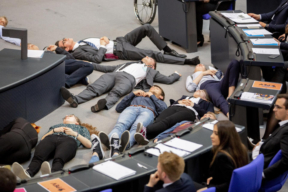 Participants of a protest action for climate justice by Fridays For Future lie on the floor in the plenary hall of the Bundestag in Berlin, Germany, Tuesday, June 4, 2019. In the simulation game "Youth and Parliament", young people slip into the role of members of the Bundestag. (Christoph Soeder/dpa via AP)