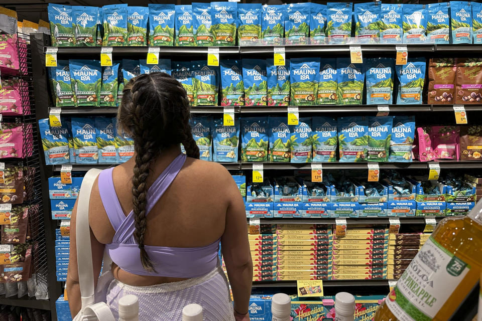 A person looks at packages of macadamia nuts at a store on Friday, April 26, 2024, in Honolulu. For decades, tourists to Hawaii have brought home gift boxes of the islands' famous chocolate-covered macadamia nuts for friends and family. (AP Photo/Audrey McAvoy)