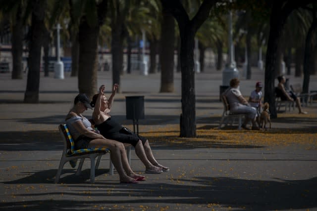 People sunbathe as they sit on park benches (Emilio Morenatti/AP)