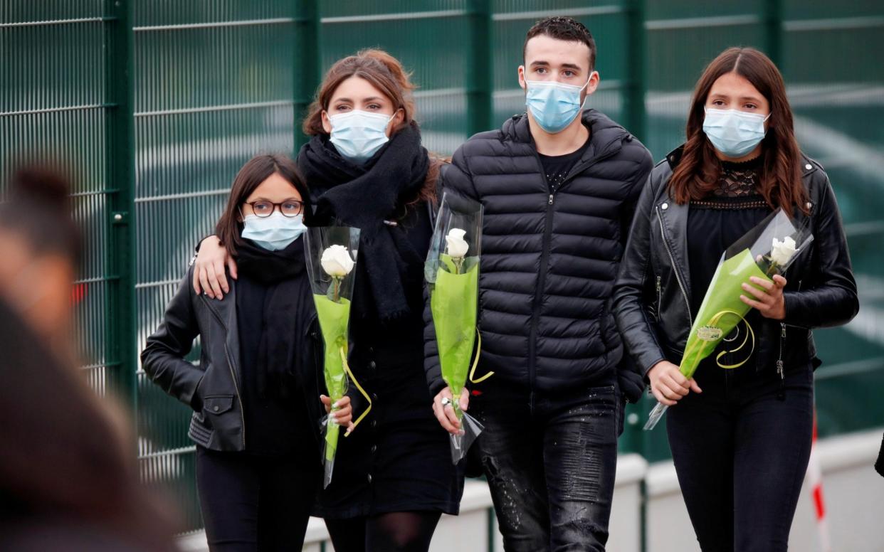 People bring flowers to the Bois d'Aulne college after the attack in the Paris suburb of Conflans St Honorine