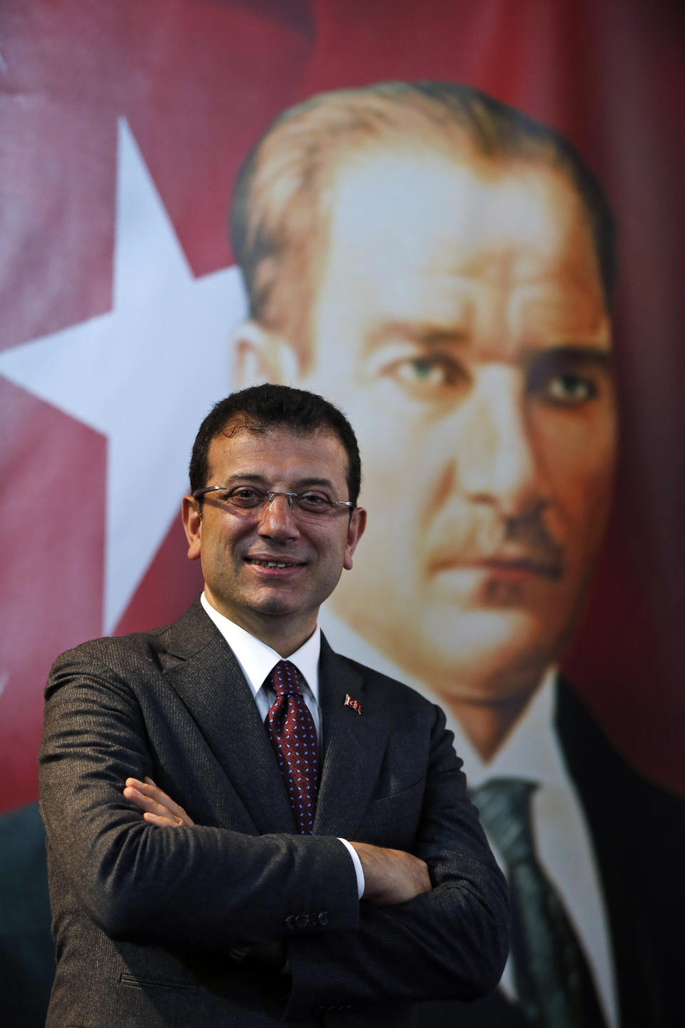 Backdropped by a poster of modern Turkey's founder Mustafa Kemal Ataturk, right, Ekrem Imamoglu, the opposition, Republican People's Party's (CHP) mayoral candidate in Istanbul, poses for The Associated Press following an interview in Istanbul, Thursday, April 4, 2019. Imamoglu said he's confident that the result of a recount of votes in the city will confirm his victory and has renewed an appeal to Turkey's President Recep Tayyip Erdogan to help end the standoff. Imamoglu won the tight race for Istanbul in Sunday's local elections in a major upset for Erdogan, who rose to power as the mayor of the city of 15 million and has said that whoever wins Istanbul wins to whole of Turkey. (AP Photo/Lefteris Pitarakis)