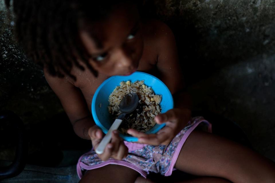Thawanny eats a lunch of rice, beans and egg in her family's house, in the Arco Iris favela (Reuters)