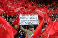 A supporter holds a banner showing support for Manchester United's Scottish manager Alex Ferguson in a sea of red flags during the English Premier League football match between Manchester United and Swansea City at Old Trafford in Manchester, northwest England, on May 12, 2013. United won 2-1